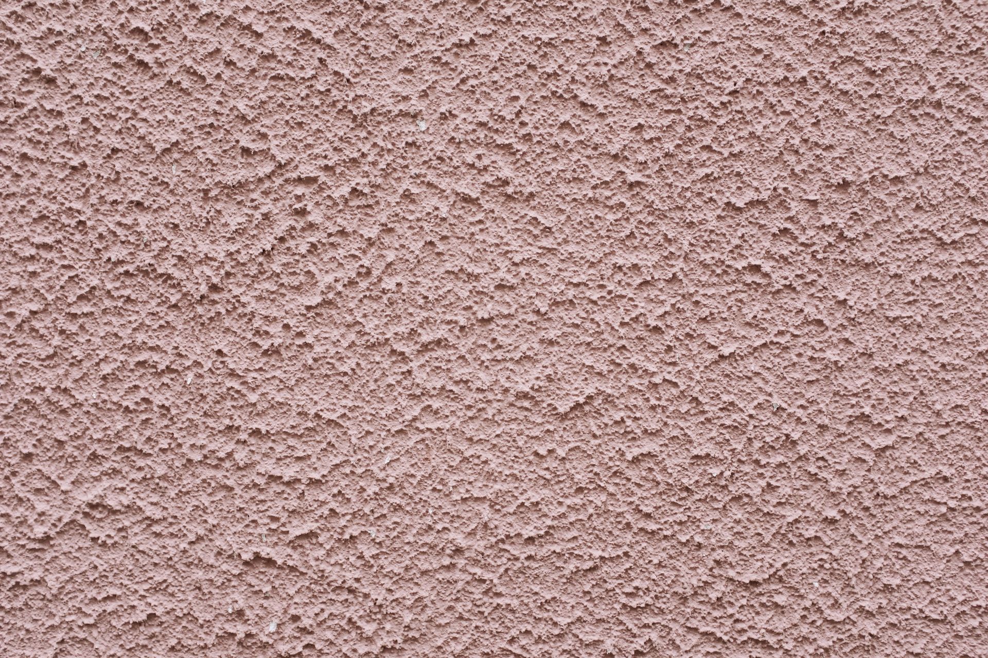 Simple background of uneven stucco pink wall surface of modern building in city