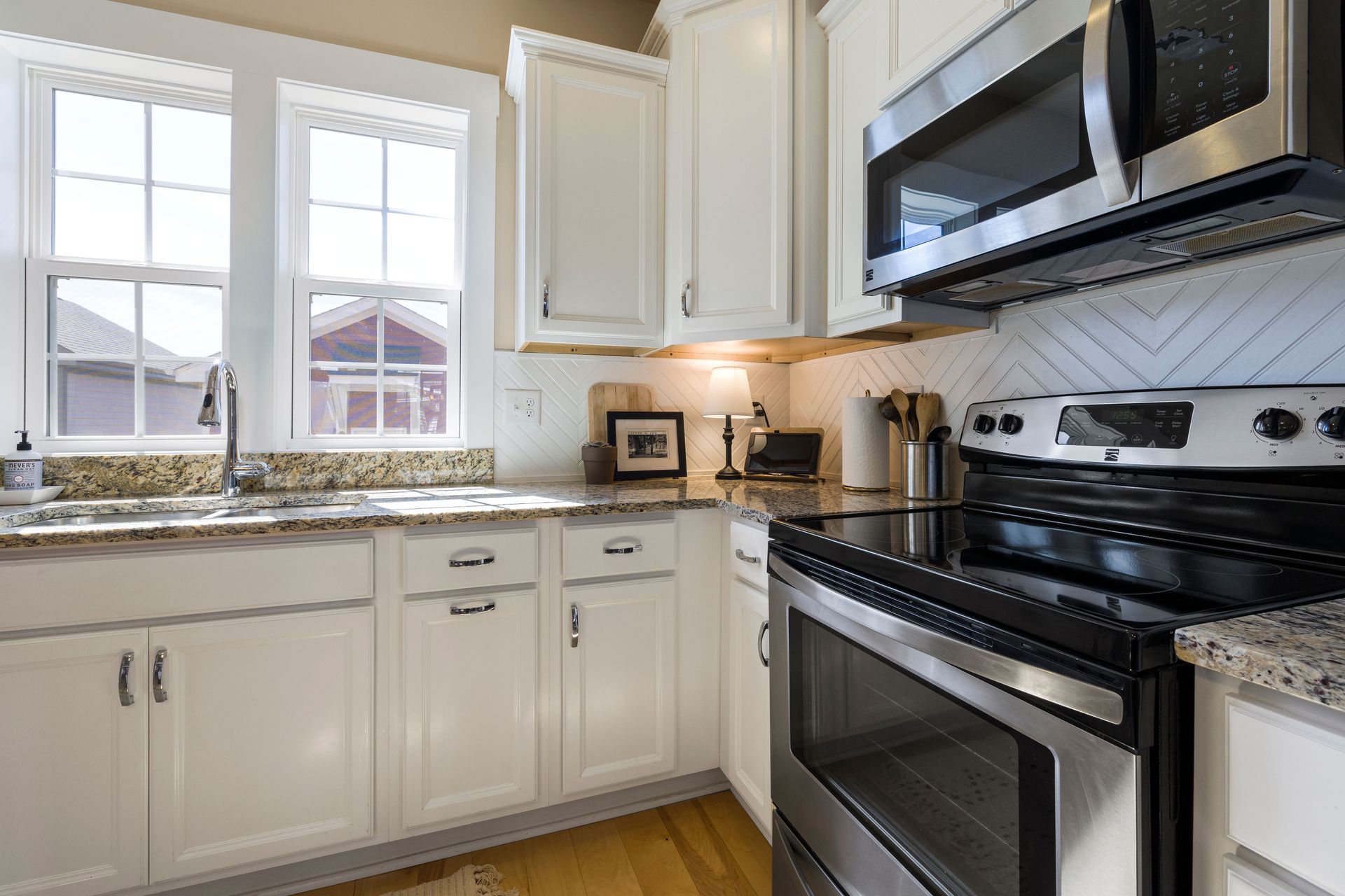 Bright and stylish modern kitchen featuring white cabinets and granite countertops with stainless steel appliances.